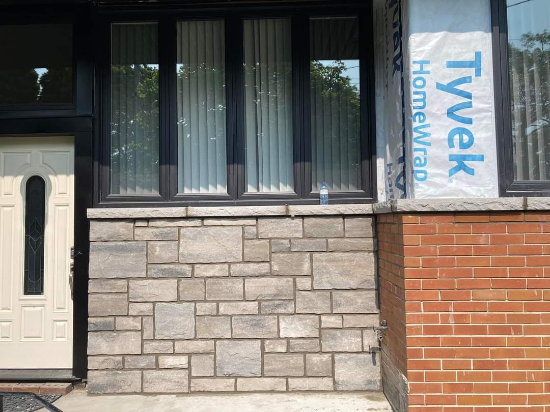 Stone veneer under a front window beside red brick and a white door